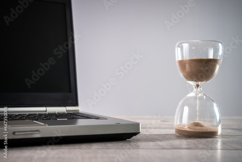 Laptop and hourglass on the table