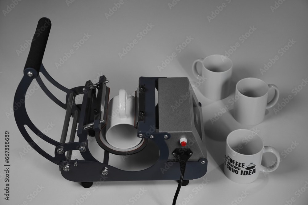 Fototapeta premium Printing logo. Heat press with cups on white table