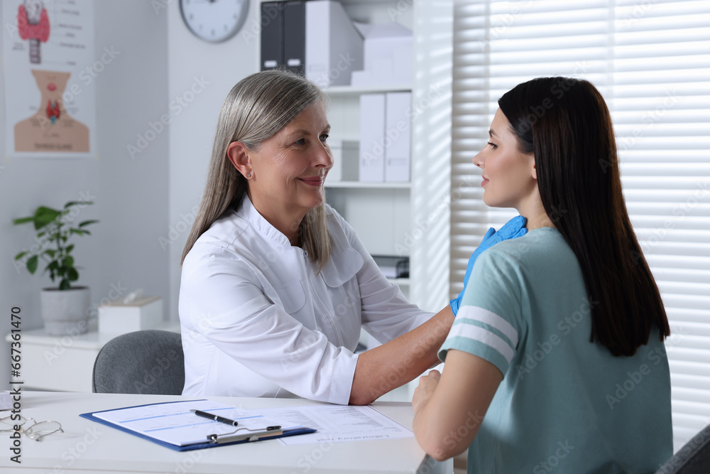 Endocrinologist examining thyroid gland of patient at table in hospital Endocrinologist examining thyroid gland of patient at table in hospital