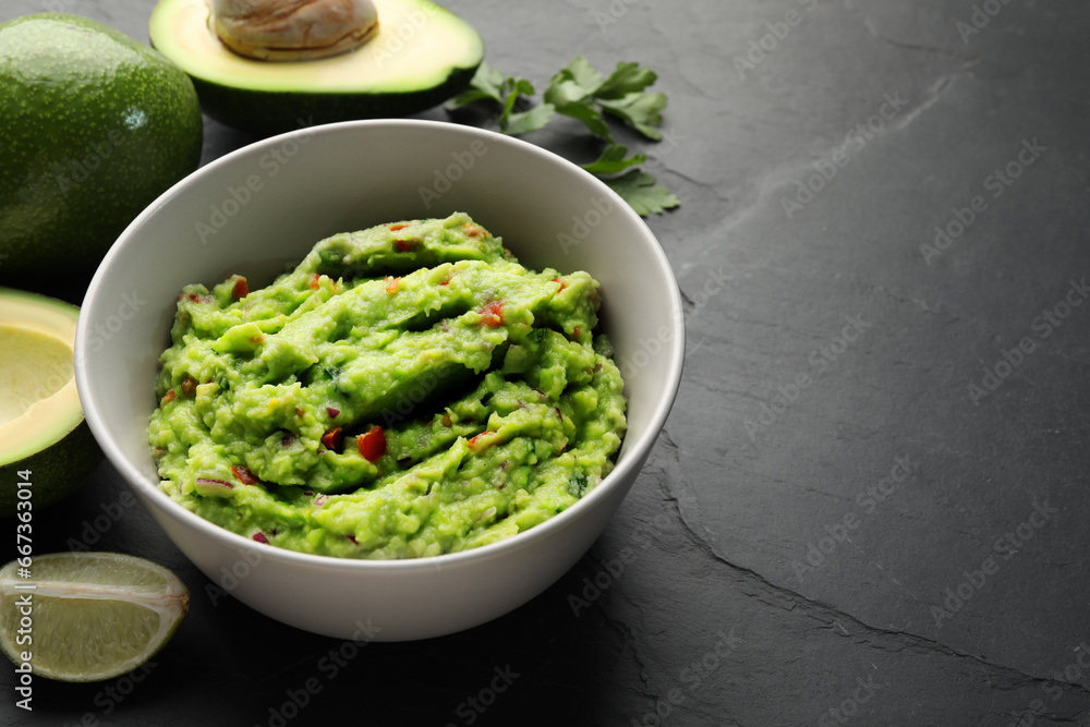 Delicious guacamole, fresh avocado and parsley on grey table. Space for text Delicious guacamole, fresh avocado and parsley on grey table. Space for text