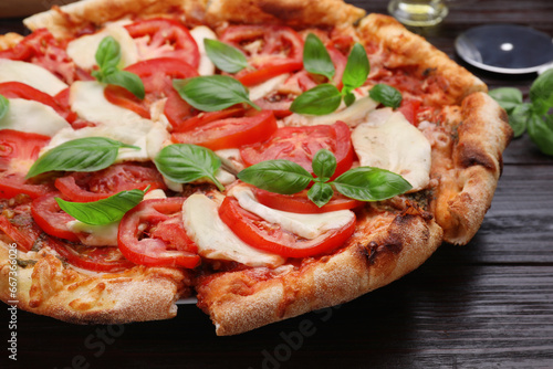 Delicious Caprese pizza on black wooden table, closeup