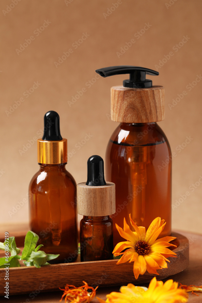 Bottles of essential oils and beautiful calendula flowers on wooden table Bottles of essential oils and beautiful calendula flowers on wooden table
