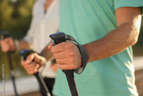 Man practicing Nordic walking with poles outdoors, closeup