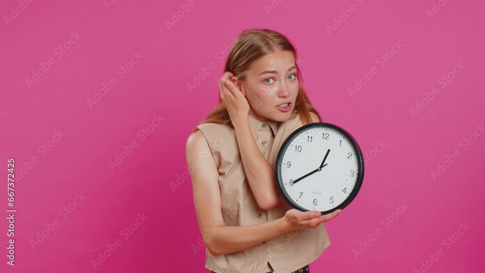 Woman with anxiety checking time on clock, running late to work, being in delay, deadline. Blonde busy girl looking at hour, minutes, worrying to be punctual isolated on pink studio background Woman with anxiety checking time on clock, running late to work, being in delay, deadline. Blonde busy girl looking at hour, minutes, worrying to be punctual isolated on pink studio background