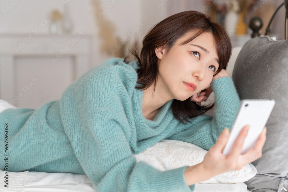 部屋でスマホを見る若い女性 考える 部屋でスマホを見る若い女性 考える
