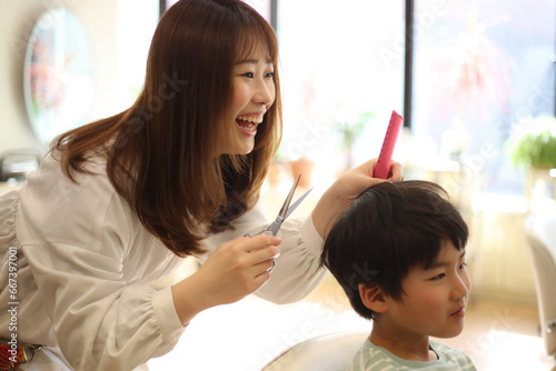 男の子の髪を切る女性美容師