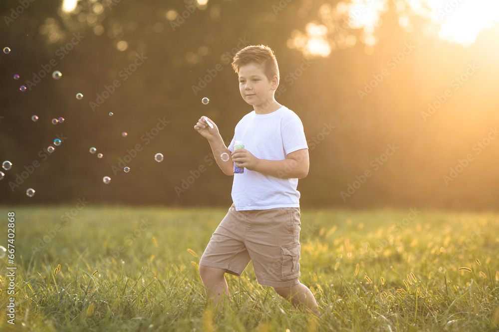 Cute little boy is playing with big soap bubbles outdoor. Child is blowing big and small bubbles simultaneously. Active summer leisure for kids. Cute little boy is playing with big soap bubbles outdoor. Child is blowing big and small bubbles simultaneously. Active summer leisure for kids.