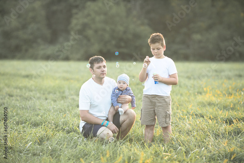 Happy family in the field. They are having fun playing and blowing bubbles.