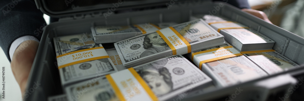 Manager holds case with counted stacks of dollar banknotes Manager holds case with counted stacks of dollar banknotes