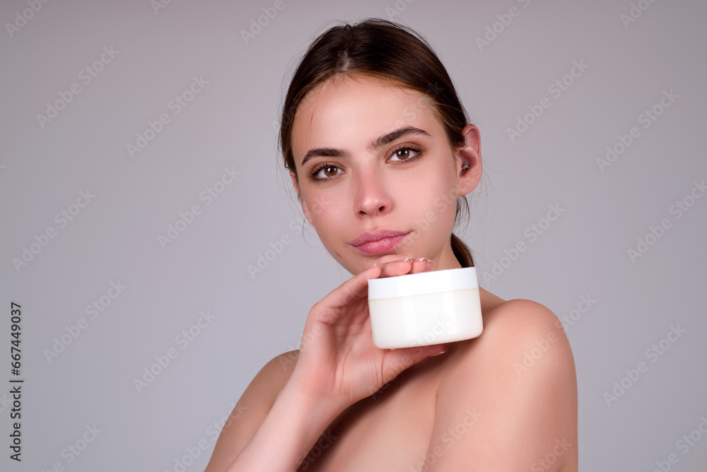 Beauty portrait of a beautiful half naked woman applying face cream isolated on studio background. Skin care product. Moisturizing creme on face. Perfect skin, morning routine. Beauty portrait of a beautiful half naked woman applying face cream isolated on studio background. Skin care product. Moisturizing creme on face. Perfect skin, morning routine.