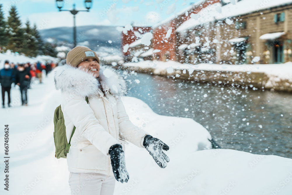 Φωτογραφία Woman tourist Visiting in Otaru, happy Traveler in Sweater sightseeing Otaru canal with Snow in winter season