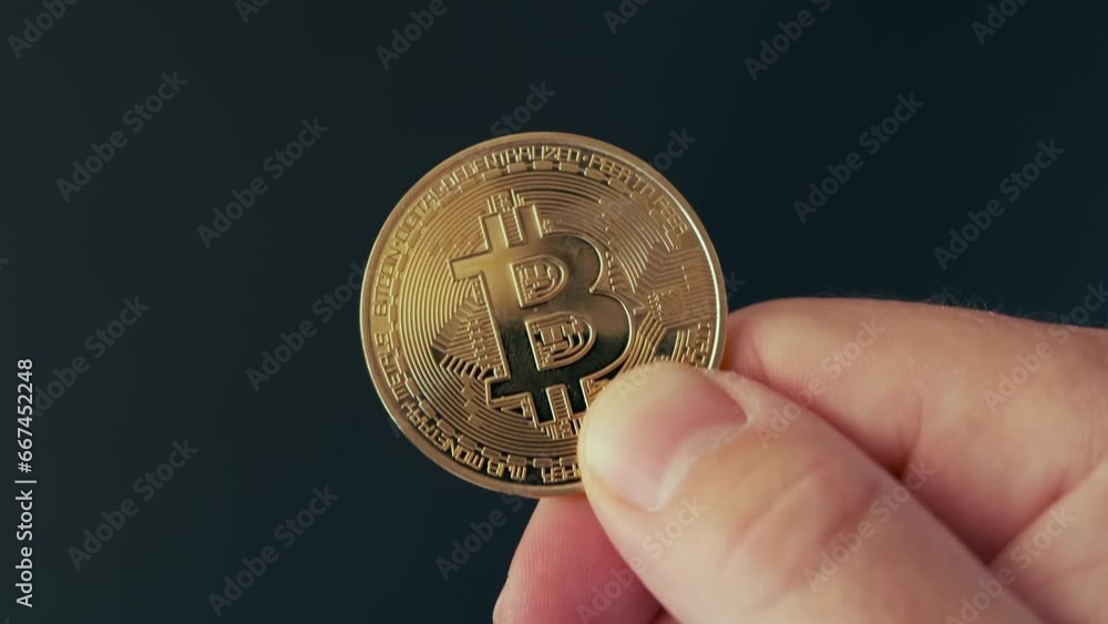 Gold coin bitcoin in hand close up. Cryptocurrency symbol in fingers on black studio isolated background. Modern virtual currency. Gold coin bitcoin in hand close up. Cryptocurrency symbol in fingers on black studio isolated background. Modern virtual currency.