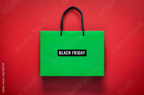 Green shopping bag with Black Friday word on red background for Black Friday shopping concept.