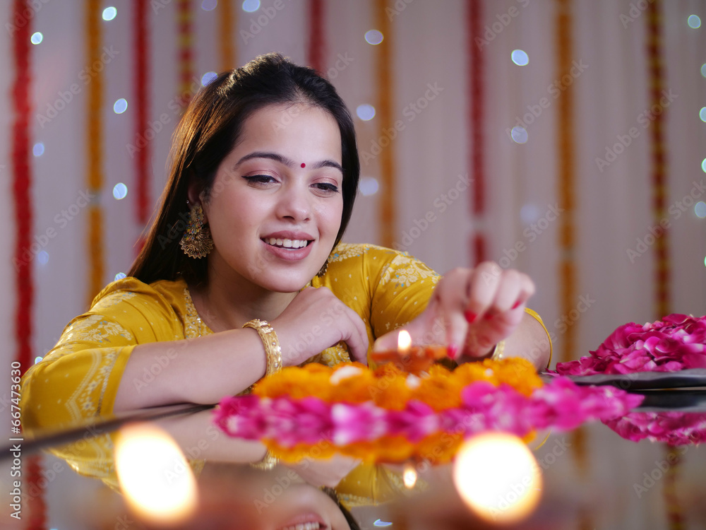 Foto de Beautiful Indian female placing a welllit oil lamp in the