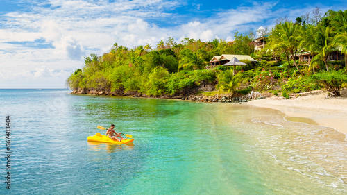 young men in a kayak on a tropical island in the Caribbean Sea, St Lucia or Saint Lucia. young man on vacation on a tropical island paddling in front of the beach with turqouse colored ocean