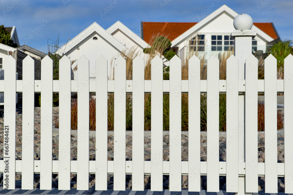 fence of a white wooden garden in front of windows on white facade of a house fence of a white wooden garden in front of windows on white facade of a house