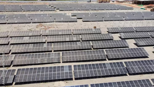 Aerial forward flying over dirty dusty bifacial solar panels at Jambur solar photovoltaic energy project site under construction in Gambia photo