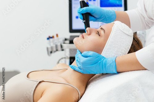 Close-up shot of a young beautiful woman lying on a couch in a cosmetology center. Young woman doing hydrofacial therapy in beauty spa.