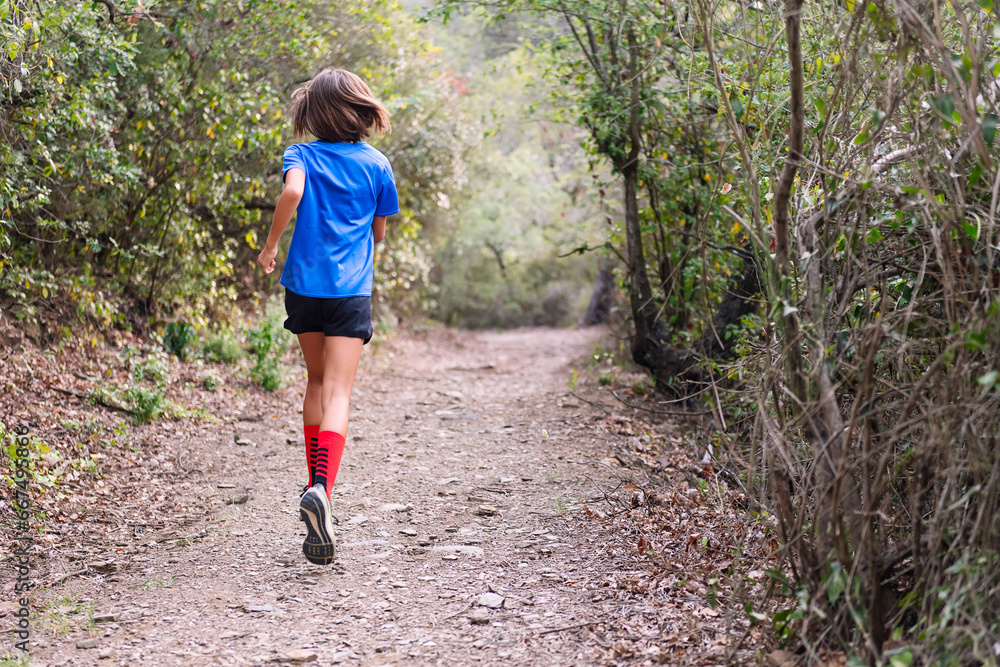 rear view of a kid practicing trail running in the forest, concept of sport in nature and healthy lifestyle for children, copy space for text rear view of a kid practicing trail running in the forest, concept of sport in nature and healthy lifestyle for children, copy space for text