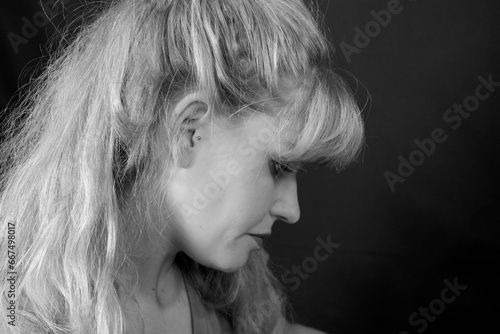 Junge blonde Frau blickt mit ernstem Gesicht an sich herunter