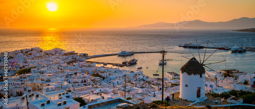 Fototapeta Naklejka Na Ścianę i Meble -  Sunset on the hills of Mykonos Greek village in Greece, the colorful old town of Mikonos village with historical windmills at sunset