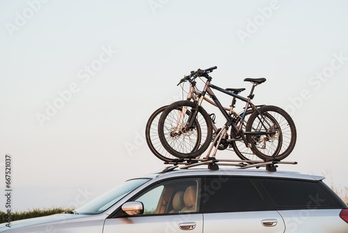 Passenger car with two bicycles mounted to the roof. Roof-mounted bikes. Sports equipment transportation.