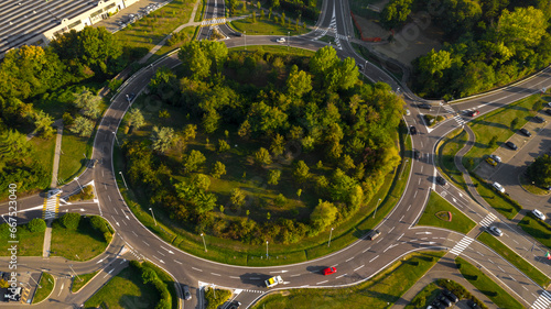 Aerial view of a large roundabout with trees in the middle. On the road there are many cars. photo