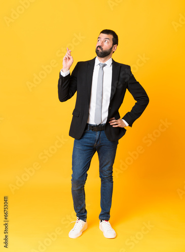 Full-length shot of business man over isolated yellow background with fingers crossing and wishing the best © luismolinero