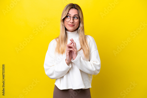 Young Uruguayan woman isolated on yellow background scheming something