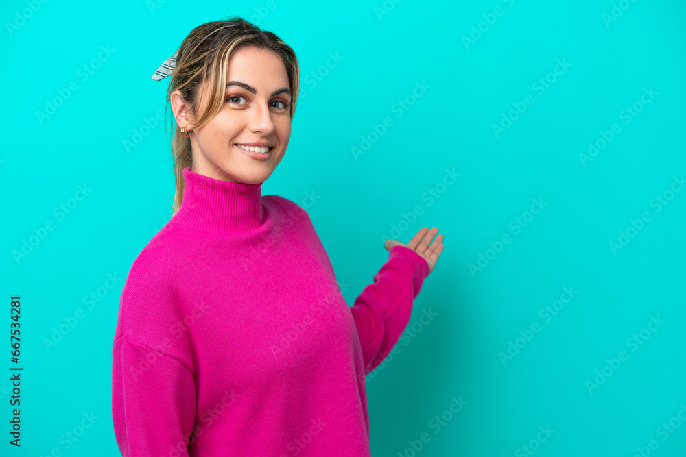 Young caucasian woman isolated on blue background extending hands to the side for inviting to come Young caucasian woman isolated on blue background extending hands to the side for inviting to come
