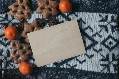 Empty wooden plate with space for text on a knit sweater featuring snowflakes with gingerbreads. Christmas holidays. New Year composition