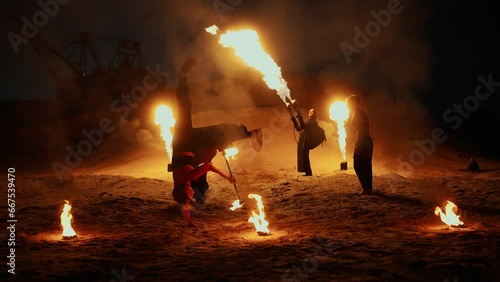 Group Of Stuntmen Performing Amazing Fire Shot Outdoors In Night, Acrobat Woman Performing Tricks photo