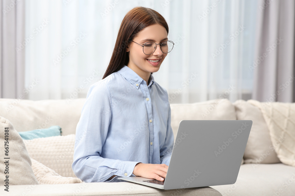 Smiling woman in stylish eyeglasses working with laptop at home Smiling woman in stylish eyeglasses working with laptop at home