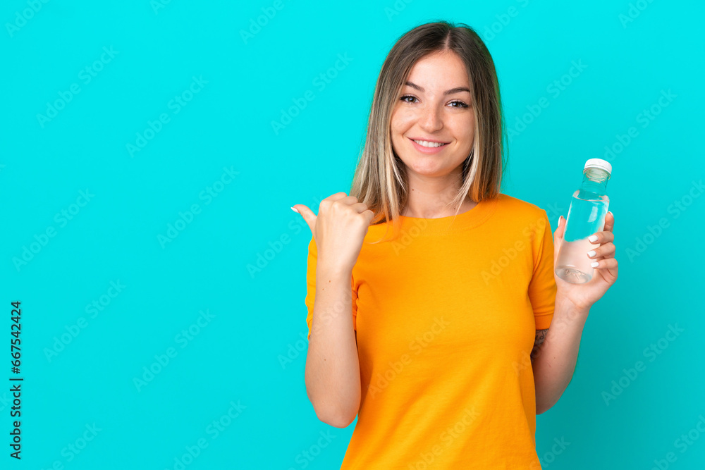 Young Romanian woman with a bottle of water isolated on blue background pointing to the side to present a product Young Romanian woman with a bottle of water isolated on blue background pointing to the side to present a product