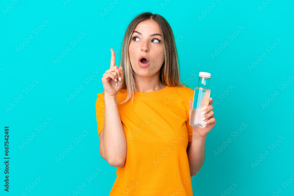 Young Romanian woman with a bottle of water isolated on blue background thinking an idea pointing the finger up Young Romanian woman with a bottle of water isolated on blue background thinking an idea pointing the finger up