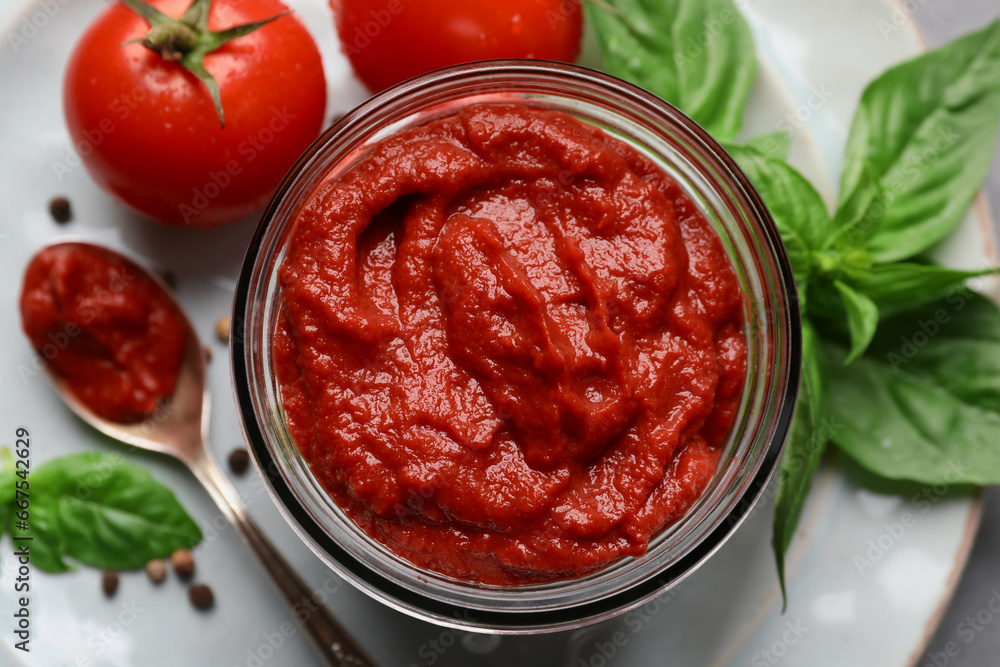Jar of tasty tomato paste and ingredients on plate, top view Jar of tasty tomato paste and ingredients on plate, top view