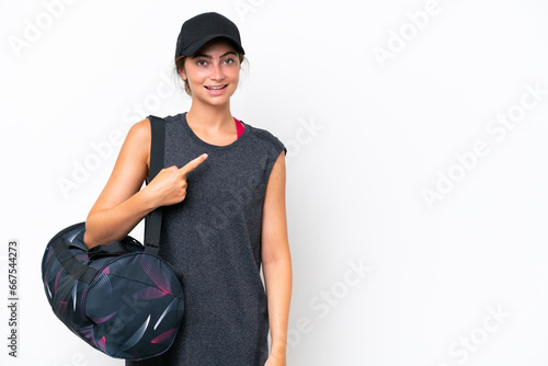 Young sport woman with sport bag isolated on white background pointing to the side to present a product