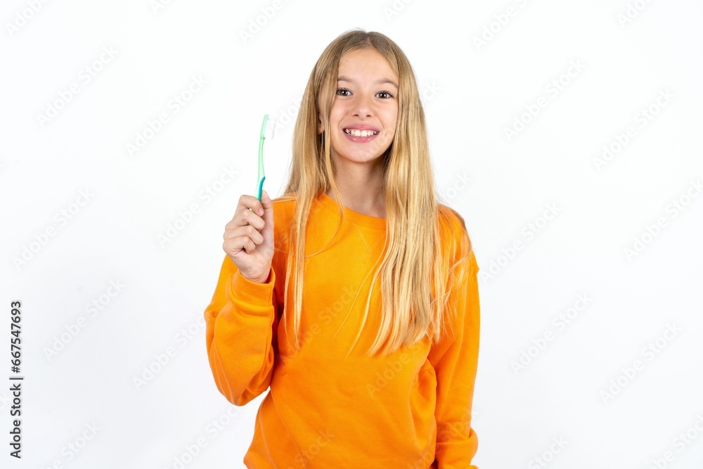 Beautiful teen blonde girl holding a toothbrush and smiling. Dental healthcare concept. Beautiful teen blonde girl holding a toothbrush and smiling. Dental healthcare concept.