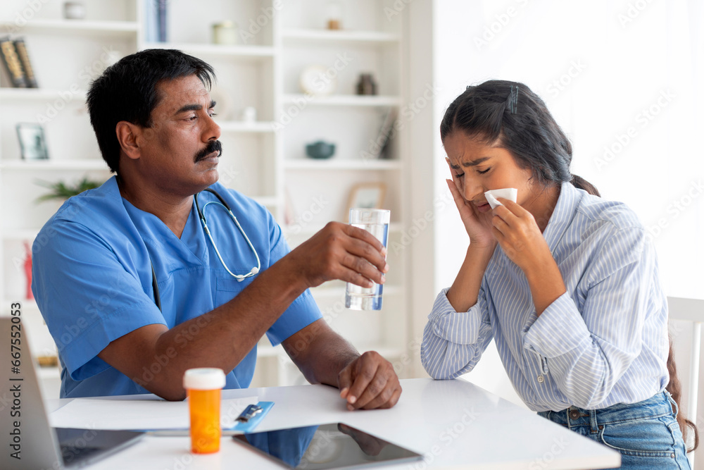 Indian doctor man comforting upset female patient crying during appointment in clinic Indian doctor man comforting upset female patient crying during appointment in clinic