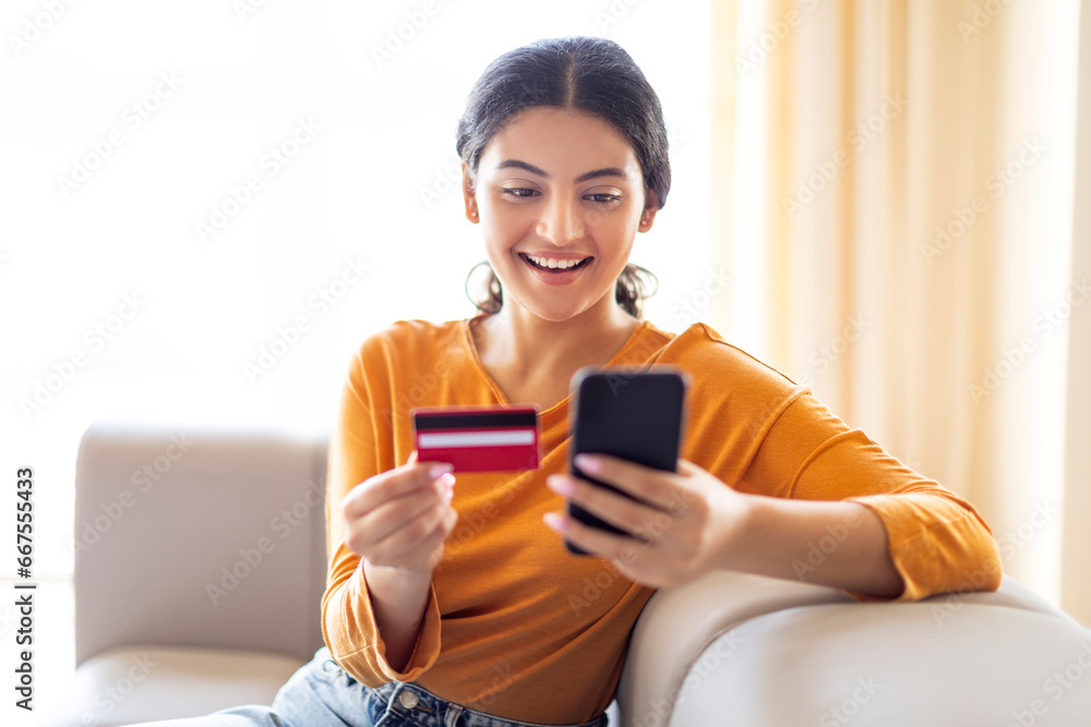 Mobile Payments. Beautiful Indian Woman Using Smartphone And Credit Card At Home Mobile Payments. Beautiful Indian Woman Using Smartphone And Credit Card At Home
