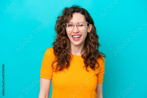 Young caucasian woman isolated on blue background With glasses and happy expression