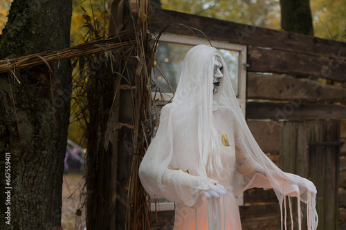 Halloween decorations, ghosts in white garments illuminated in the park