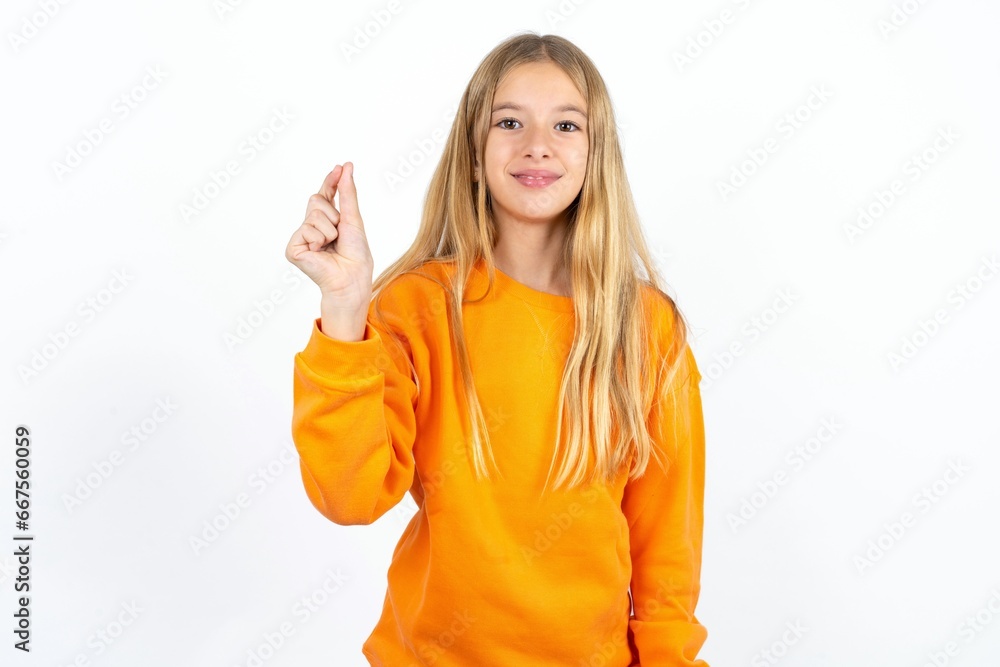 Beautiful caucasian teen girl wearing orange sweater pointing up with hand showing up seven fingers gesture in Chinese sign language QÄ«. Beautiful caucasian teen girl wearing orange sweater pointing up with hand showing up seven fingers gesture in Chinese sign language QÄ«.