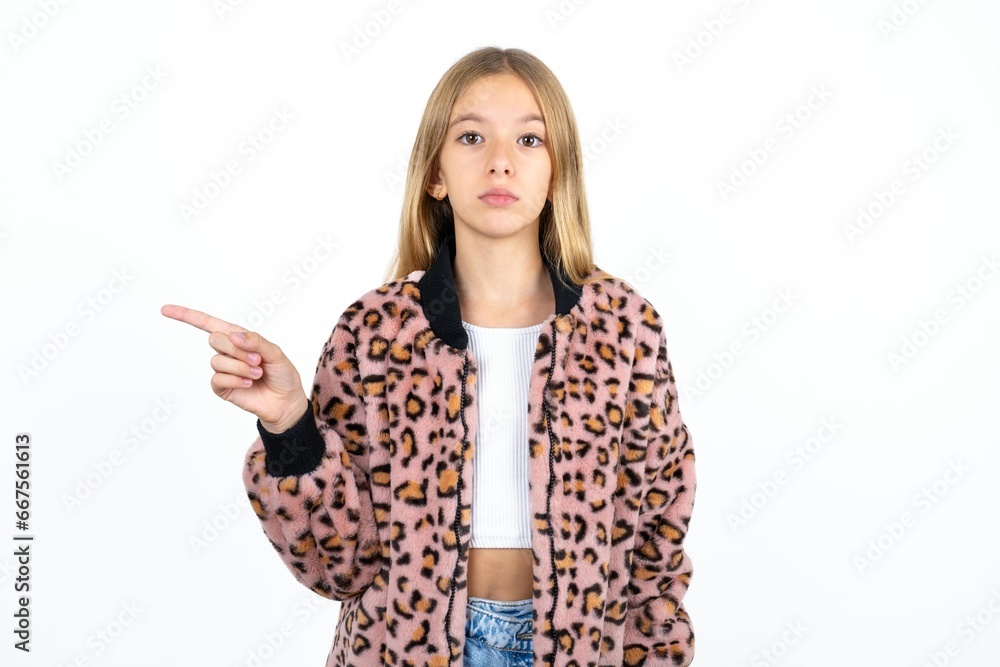 Beautiful caucasian teen girl points to side on blank space demonstrates advertisement. People and promotion concept Beautiful caucasian teen girl points to side on blank space demonstrates advertisement. People and promotion concept