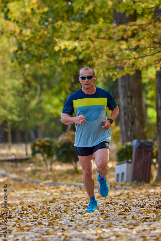 Portrait of a middle-aged man running in the park on an autumn day.
