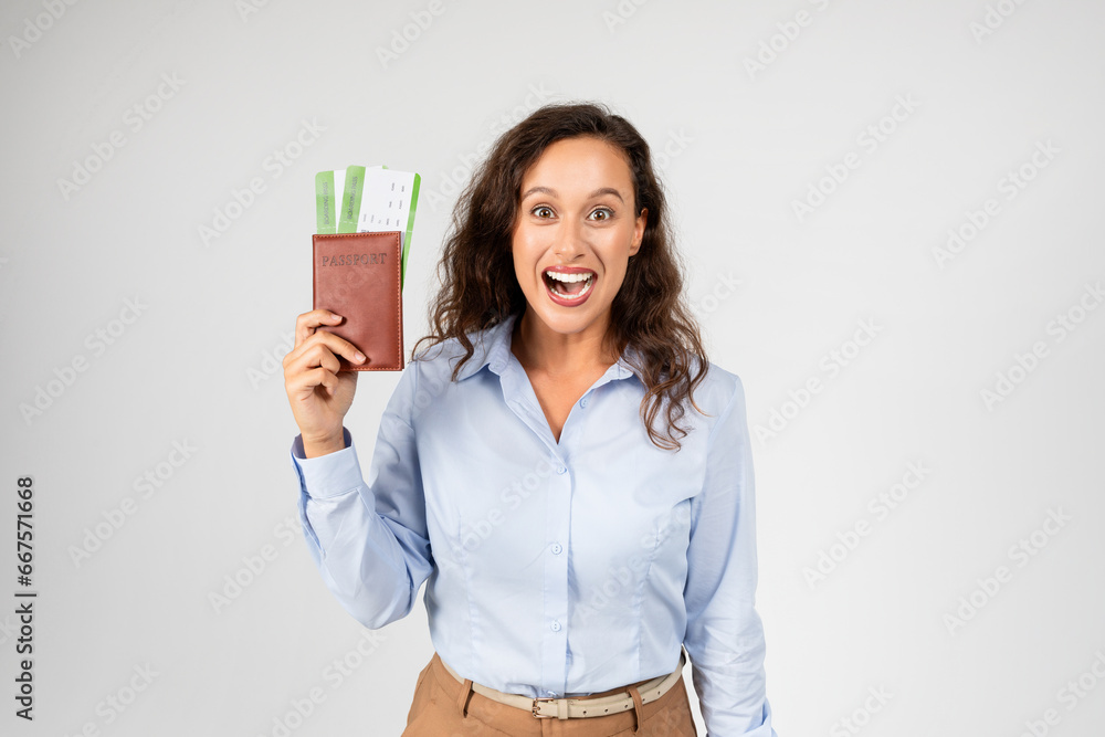 Woman at work shocked, holding a flyticket and passport, showing surprised facial expression Woman at work shocked, holding a flyticket and passport, showing surprised facial expression