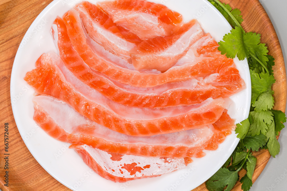 Salted salmon bellies on dish and cilantro on wooden stand Salted salmon bellies on dish and cilantro on wooden stand