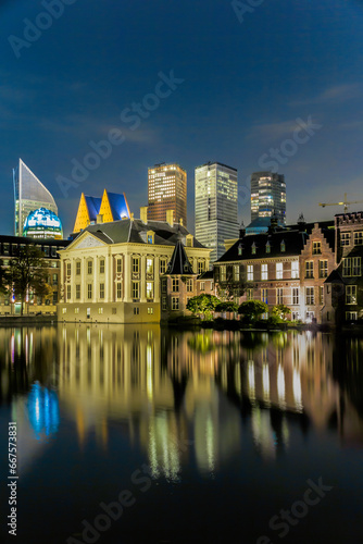 The Hague's stunning skyline comes to life at twilight, where modern skyscrapers meet historic architecture along the calm waters, creating a harmonious reflection that unites old with new in the Neth