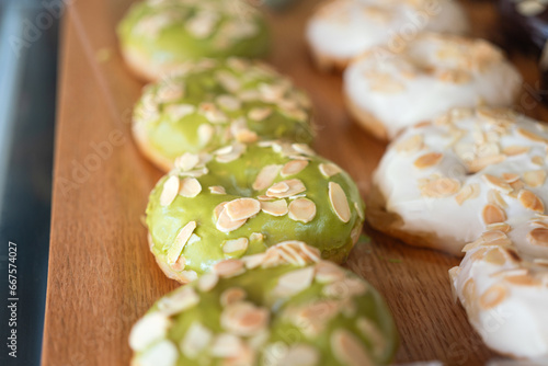 Row of macha green tea chocolate topping with almond donuts which are prepared for sale at the bakery shop. Sweet food object photo.