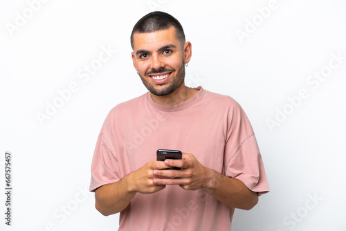 Young caucasian man isolated on white background sending a message with the mobile © luismolinero
